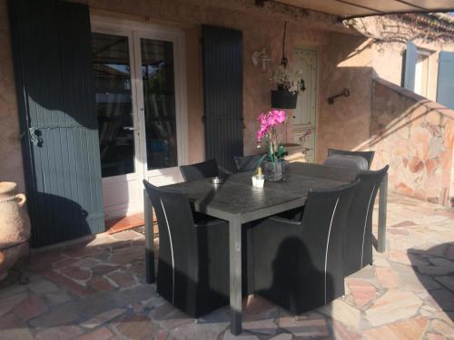 une table noire et des chaises sur une terrasse dans l'établissement Grande villa, au Muy