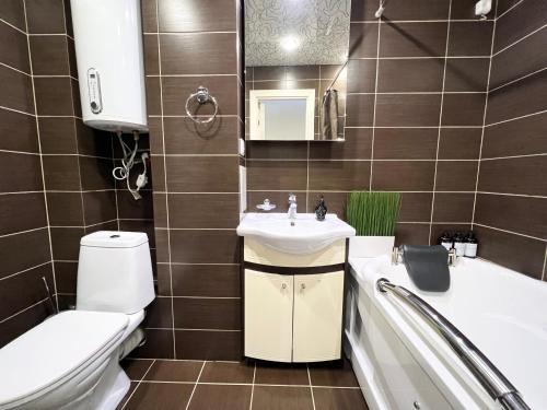 uma casa de banho com um lavatório, um WC e uma banheira em Апартаменты LUX + em Pavlodar