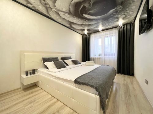 1 dormitorio con 1 cama grande y una pintura en el techo en Апартаменты LUX +, en Pavlodar