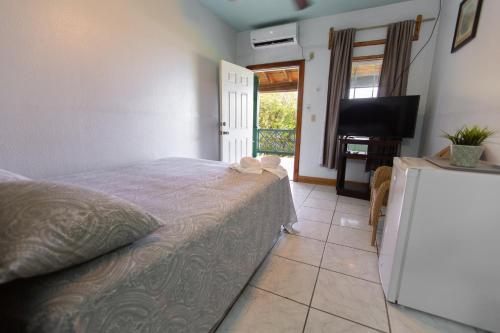a bedroom with a bed and a television and a tiled floor at Sea Eye Hotel - Laguna Building in Utila