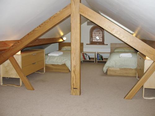a attic bedroom with two beds and a window at Red House Farm Cottage in Whitegate