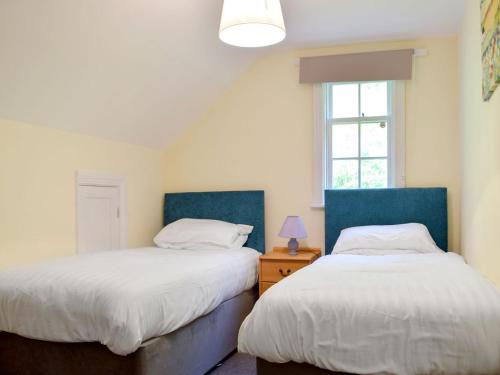a bedroom with two beds and a window at The Gate House in Pendine