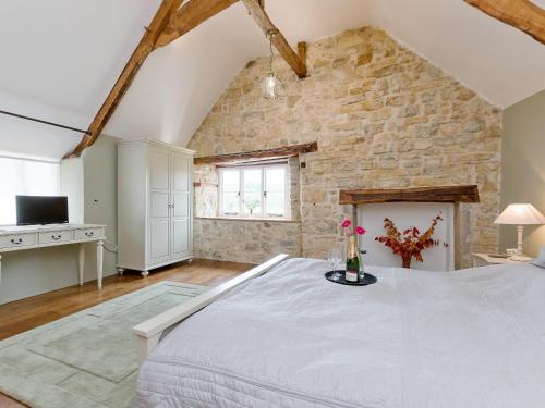 um quarto com uma grande cama branca e uma parede de pedra em The Farmhouse At Higher Westwater em Axminster