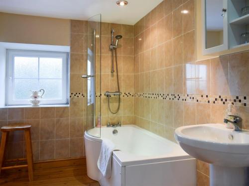 a bathroom with a tub and a sink and a shower at Penrhiw in Llangeitho