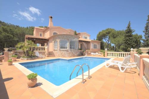 a villa with a swimming pool in front of a house at TORRE DON BENITO - Large home, sea views & pool in Begur
