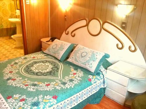 a bedroom with a bed with a floral blanket and pillows at Hotel Di Maurier in Santiago