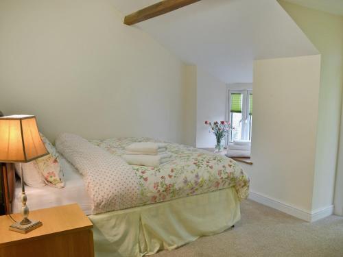 1 dormitorio con 1 cama y 1 mesa con lámpara en Birch Lodge en Lamerton
