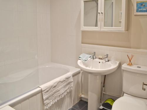 a white bathroom with a sink and a toilet at The Broomes in Whitstable