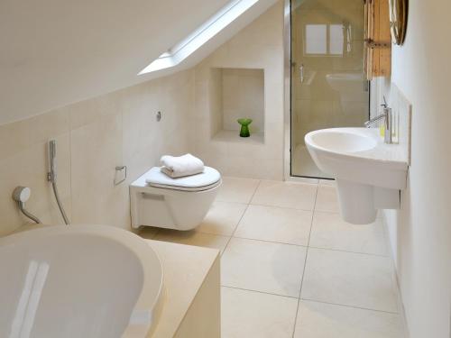 a white bathroom with a toilet and a sink at Chapel Cottage in Sharrington