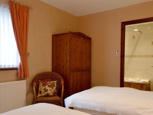 1 dormitorio con 2 camas, armario y silla en Copper View, en Coniston
