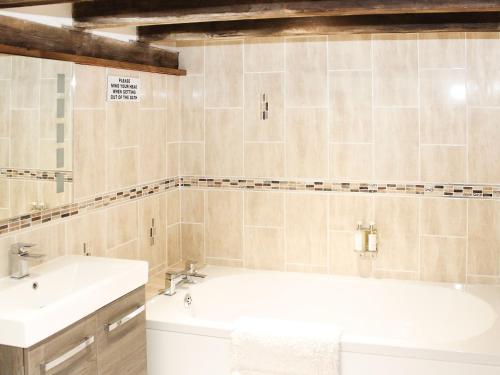 a bathroom with a white tub and a sink at The Cart Shed in Tickton