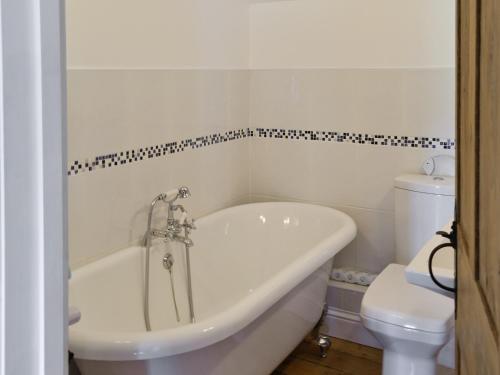 a white bath tub in a bathroom with a toilet at Shrubberies Cottage - Dc5472 in Skinningrove