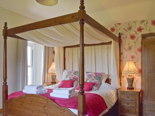 a bedroom with a canopy bed with pink sheets at The Sycamores in Clynderwen
