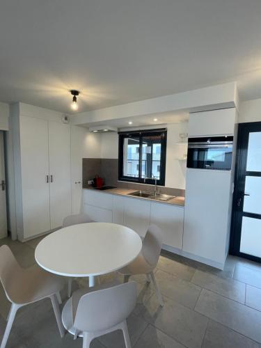 a white kitchen with a white table and chairs at Les Cyclistes : appartement Vintoux in Malaucène