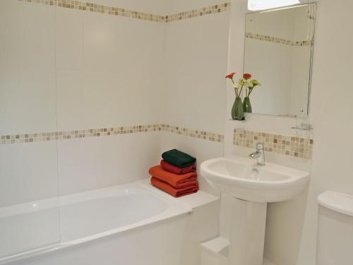 een witte badkamer met een wastafel en een bad bij Tiger in Horsted Keynes