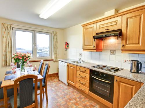 a kitchen with wooden cabinets and a table with a dining room at Mull in Achnacroish