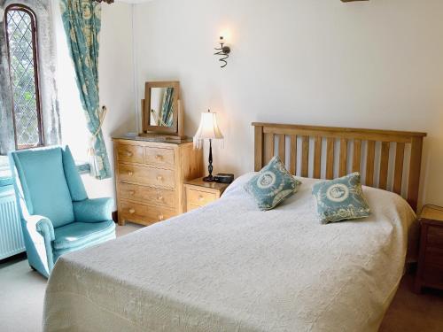 a bedroom with a bed and a blue chair at The Manor Wing in Par