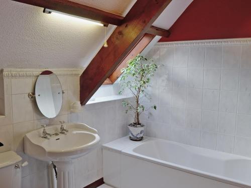 a bathroom with a sink and a mirror and a tub at The Manor Wing in Par