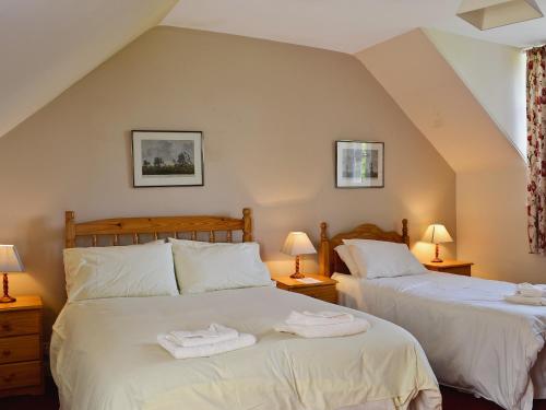 two twin beds in a room with two lamps at Kennedy Cottage in Straiton