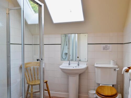 a bathroom with a sink and a toilet and a window at Kennedy Cottage in Straiton