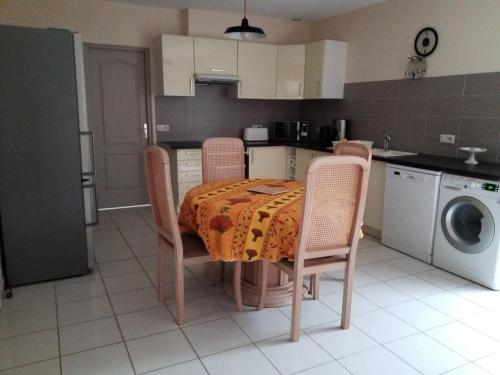 une cuisine avec une table et des chaises avec une table et une machine à laver dans l'établissement Nos penates, à Bagnols-en-Forêt