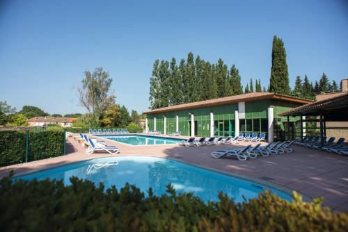une piscine avec des chaises longues et un bâtiment dans l'établissement Belambra Clubs L'Isle Sur La Sorgue - Domaine De Mousquety, à LʼIsle-sur-la-Sorgue