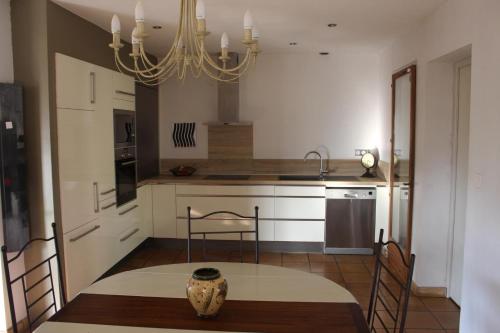 une cuisine avec une table et des chaises ainsi qu'un lustre dans l'établissement Maison les hortensias, à Montauroux