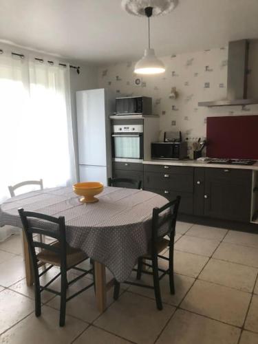 une cuisine avec une table et des chaises ainsi qu'une cuisine avec une table et une table dans l'établissement Proche Bioparc Maison avec jardin, à Doué-la-Fontaine