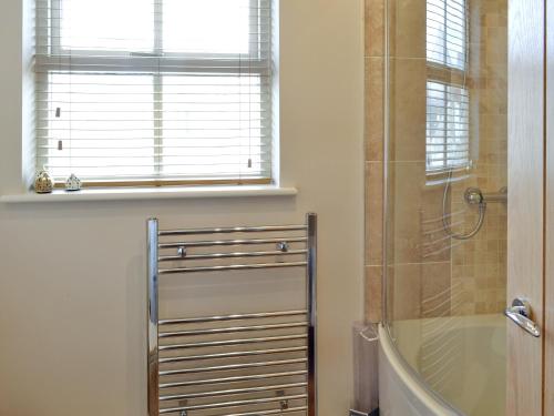 a bathroom with a shower and a tub and a window at Peel Post Office Apartment in Peel