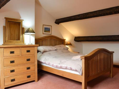 ホークスヘッドにあるTarns Cottageのベッドルーム(木製ベッド1台、ドレッサー付)
