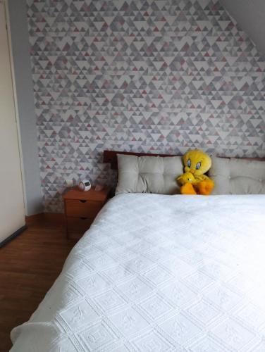 un ours en peluche jaune assis au-dessus d'un lit dans l'établissement Le jardin aux oiseaux, à Saint-Jouan-de-lʼIsle
