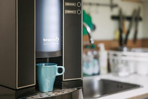 a coffee machine with a blue cup on a counter at Lugnåsberget Ekohotell in Mariestad