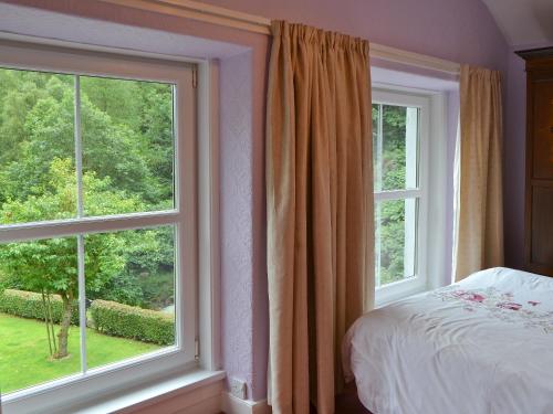 a bedroom with two large windows and a bed with a bedspread at Oak Lea in Braithwaite