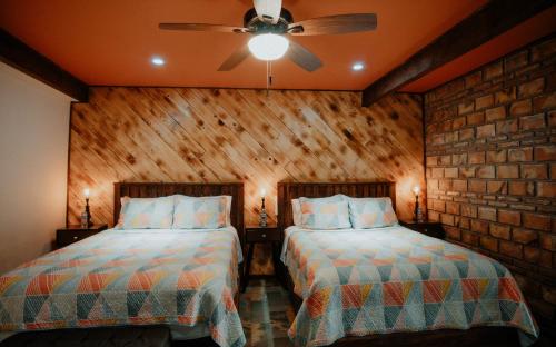 a bedroom with two beds and a ceiling fan at Cabaña R y A Valle de Guadalupe in Valle de Guadalupe