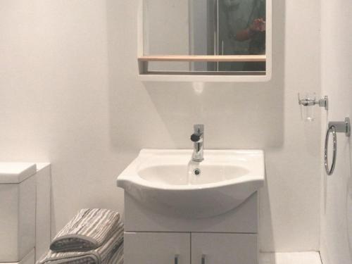 a white bathroom with a sink and a mirror at Fleet Cottage in Portree