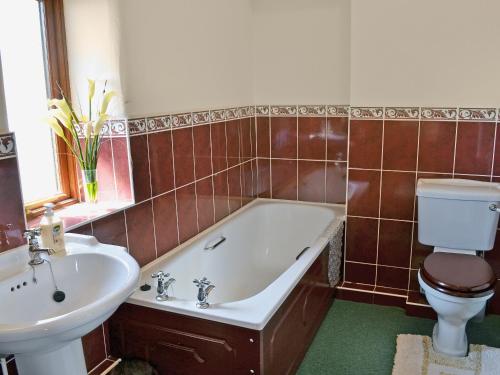 een badkamer met een bad, een toilet en een wastafel bij The Barn in Parkham