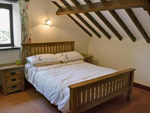 a bedroom with a wooden bed with white sheets at The Barn in Parkham