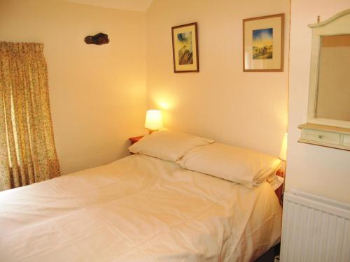 a small bedroom with a white bed with a lamp at Foxhole in Threlkeld
