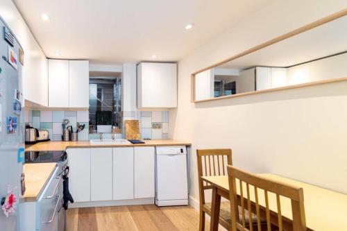 een keuken met witte kasten en een tafel en stoelen bij GuestReady - Blue surprise near St Paul's in Londen