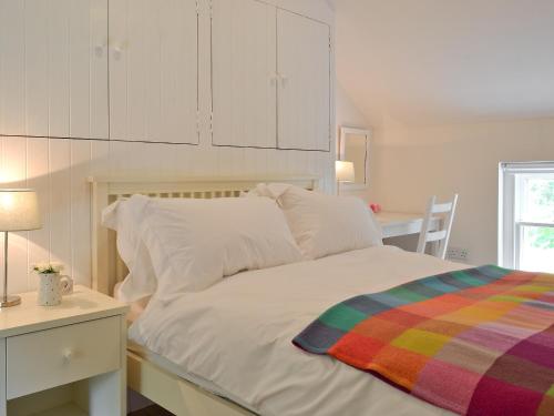 a bedroom with a white bed with a desk and a table at Llangrannog in Llandyssiliogogo