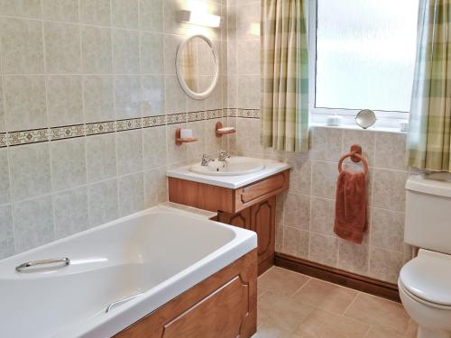 a bathroom with a tub and a sink and a toilet at South Cleeve Bungalow in Otterford