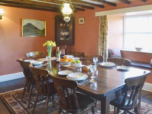 a dining room with a wooden table and chairs at Birkerthwaite Farmhouse in Eskdale