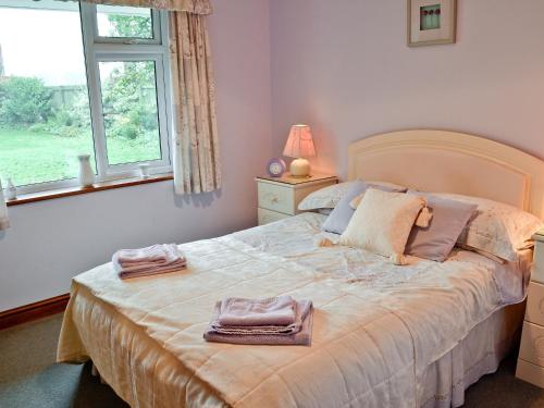 a bedroom with a bed with two towels on it at South Cleeve Bungalow in Otterford