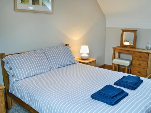 a bedroom with a bed with blue towels on it at Aden Barn in Allonby