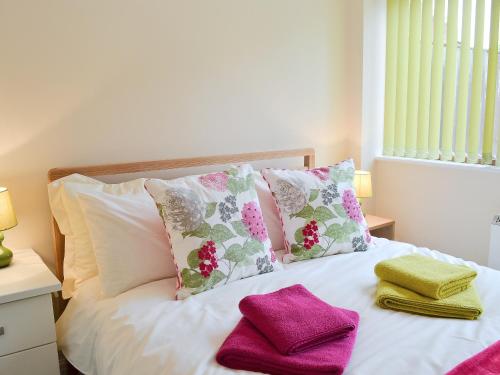 a white bed with pink and green towels on it at Garden Cottage in Bridlington