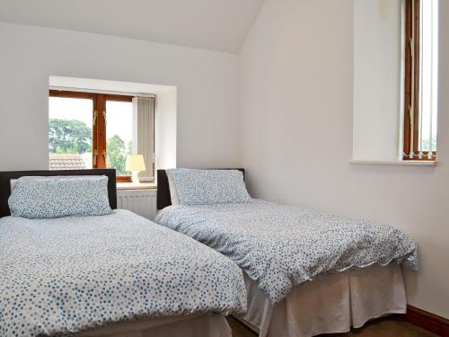 a bedroom with two beds and a window at Roslyn Cottage in Hamsterley