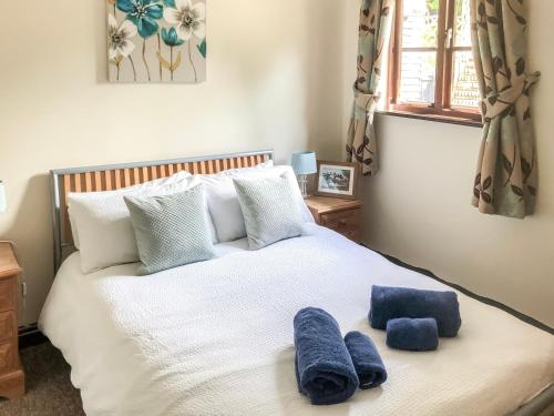 a bedroom with a white bed with blue towels on it at Lake House Cottage in Finchingfield