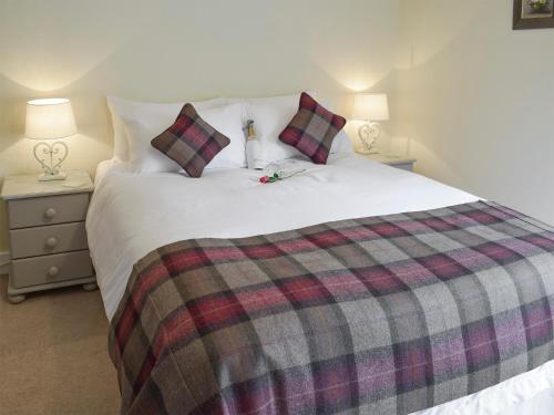 a bedroom with a large white bed with a plaid blanket at Sandhaven in Culross
