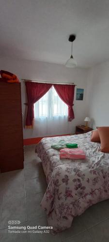 a bedroom with a bed and a window with red curtains at Complejo Veleta de Mar in Las Grutas