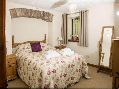 - une chambre avec un grand lit et un miroir dans l'établissement Curlew Cottage, à Great Blencow